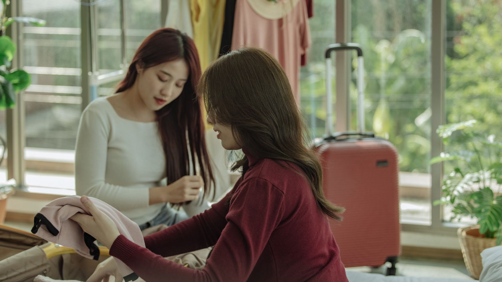A photo of two women carefully choosing what clothes to pack.