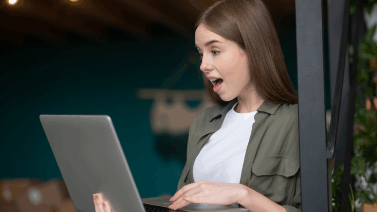 A photo of a woman looking shocked while scanning something in her laptop.
