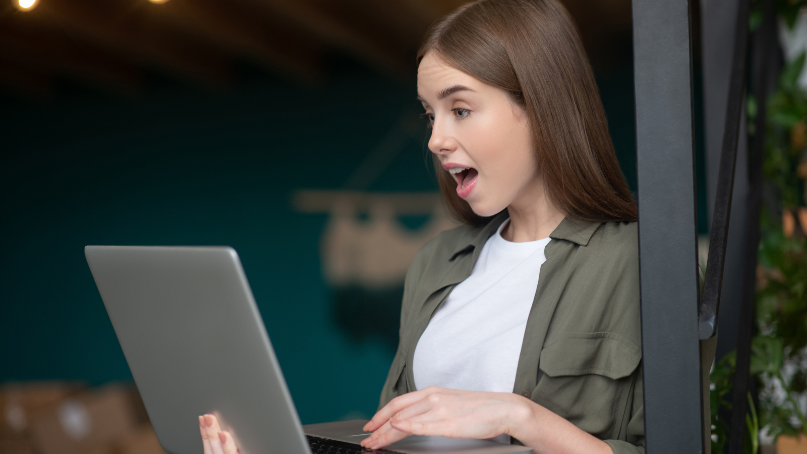 A photo of a woman looking shocked while scanning something in her laptop.