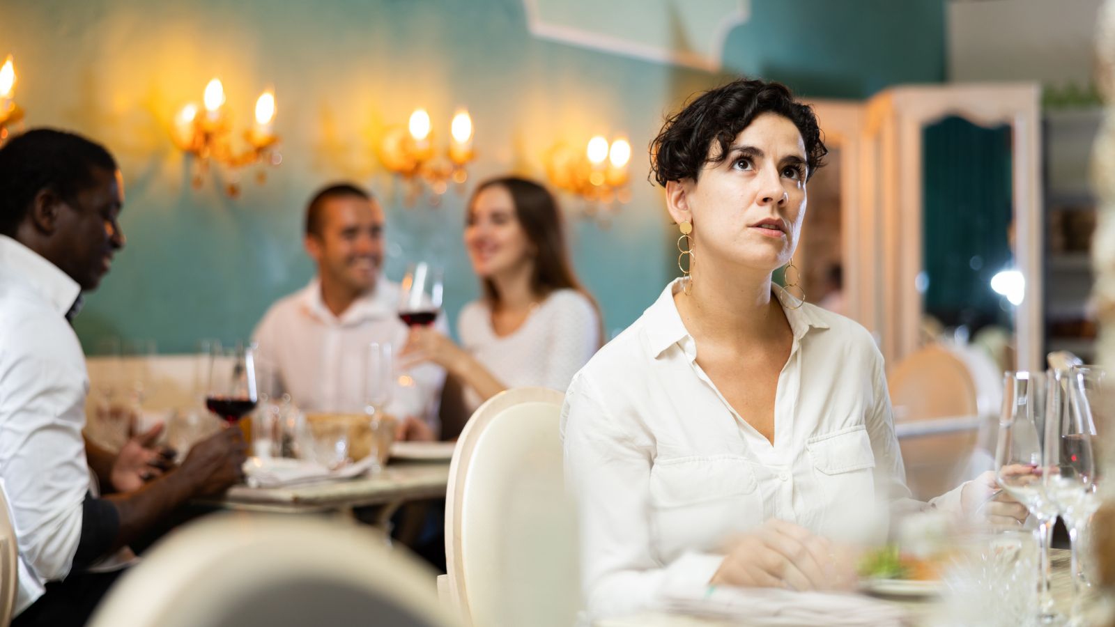 A photo of a woman in a dinner set, looking around and annoyed in the packed restaurant.