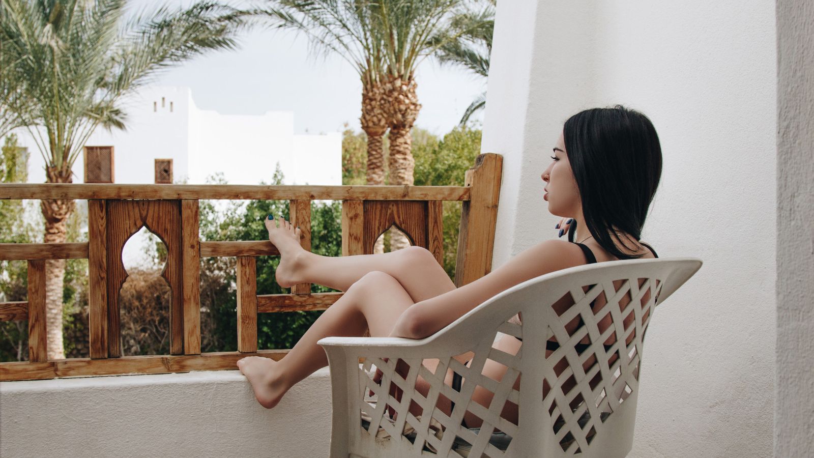 A photo of relaxed traveler in peaceful hotel room, soft natural light, private balcony or courtyard, serene and comfortable.