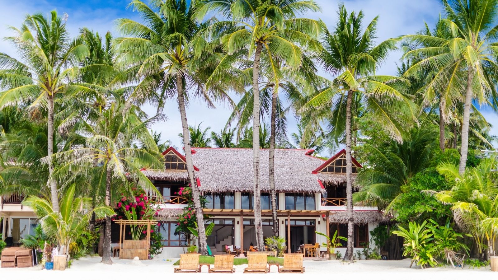 Luxury villa and palm trees around at beautiful exotic white sandy beach.