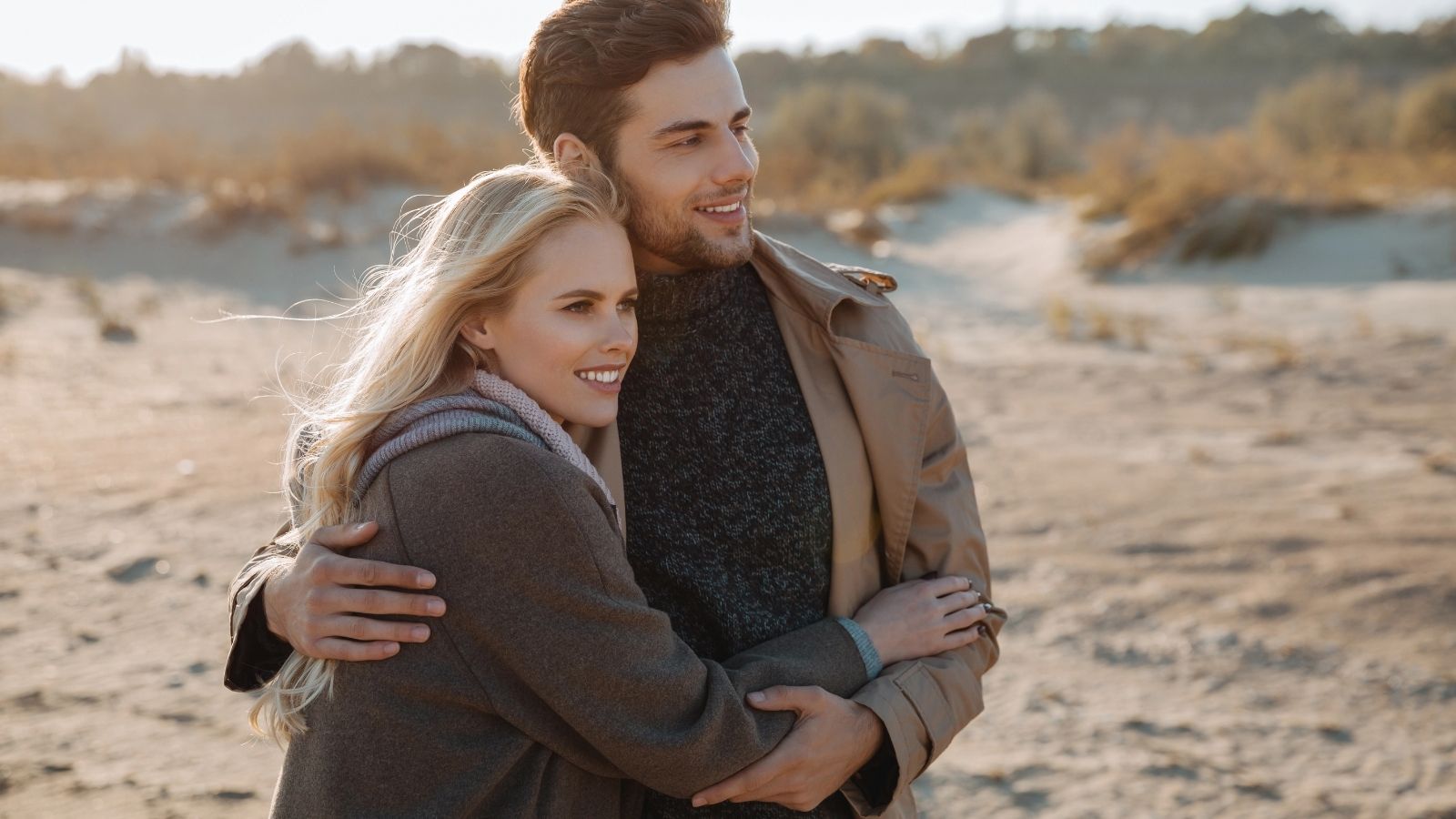 A man and a woman embracing each other while looking at something.