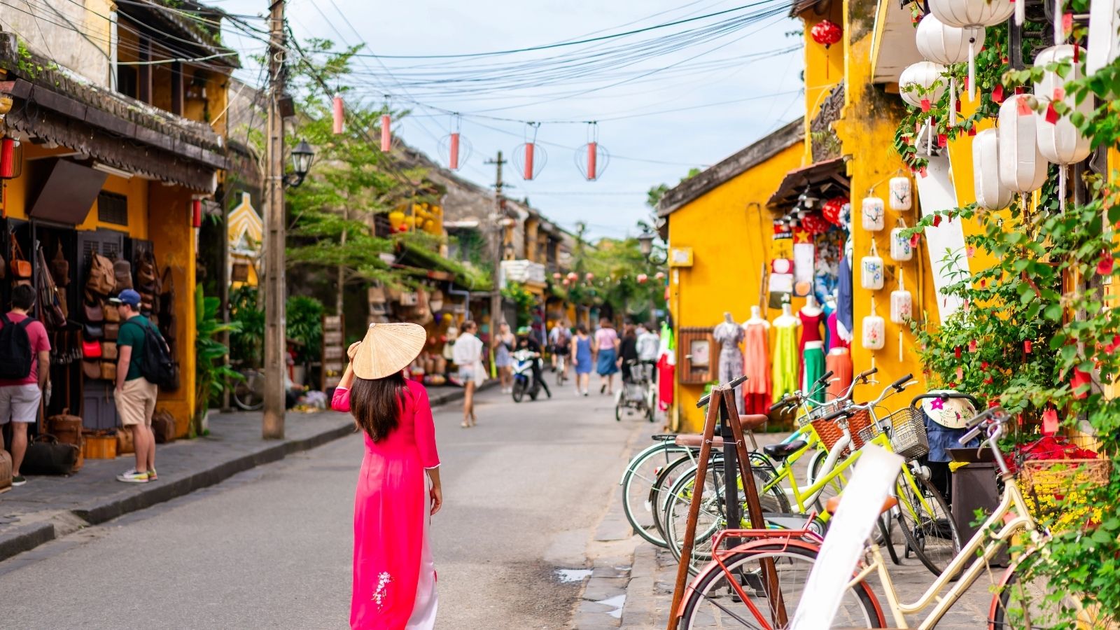 A female tourist in Vietnamese traditional dress walking at Hoi An Ancient town in Vietnam