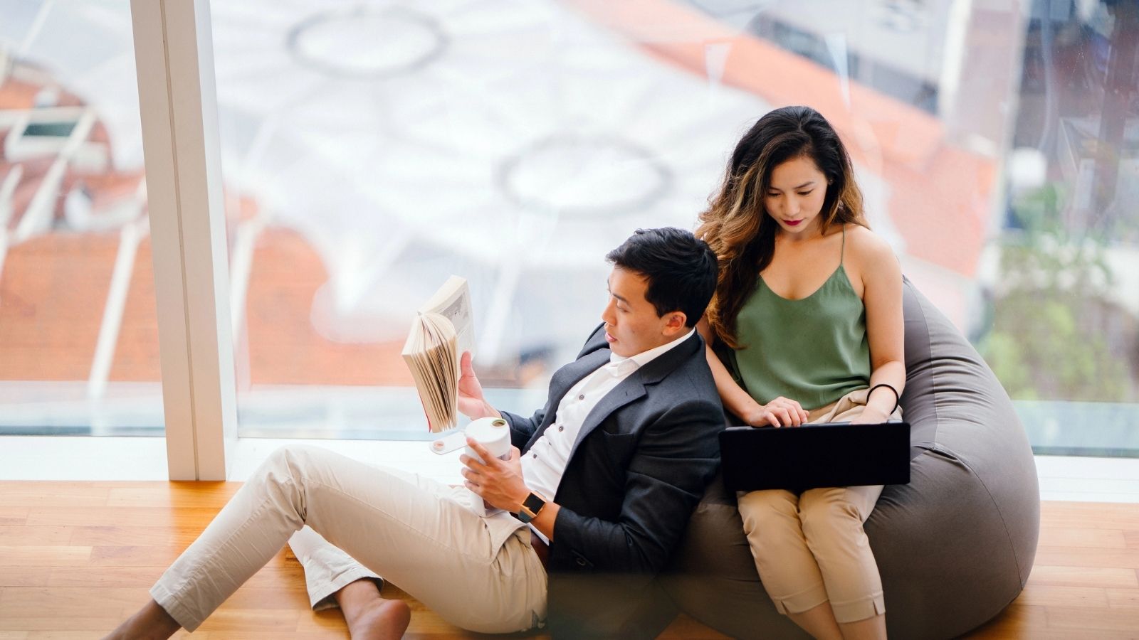 A man sitting on the floor leaning on the girl sitting on a bean bag.