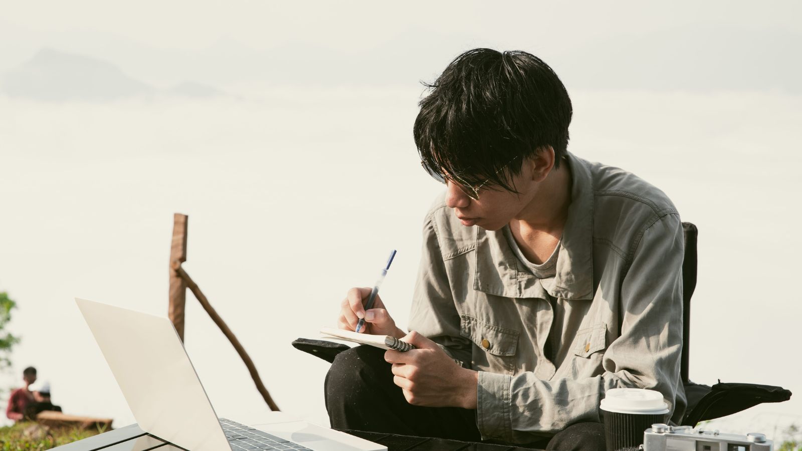 A photo of a traveler reading hotel reviews on laptop or tablet taking notes comparing options focused thoughtful realistic travel moment indoor natural light candid.