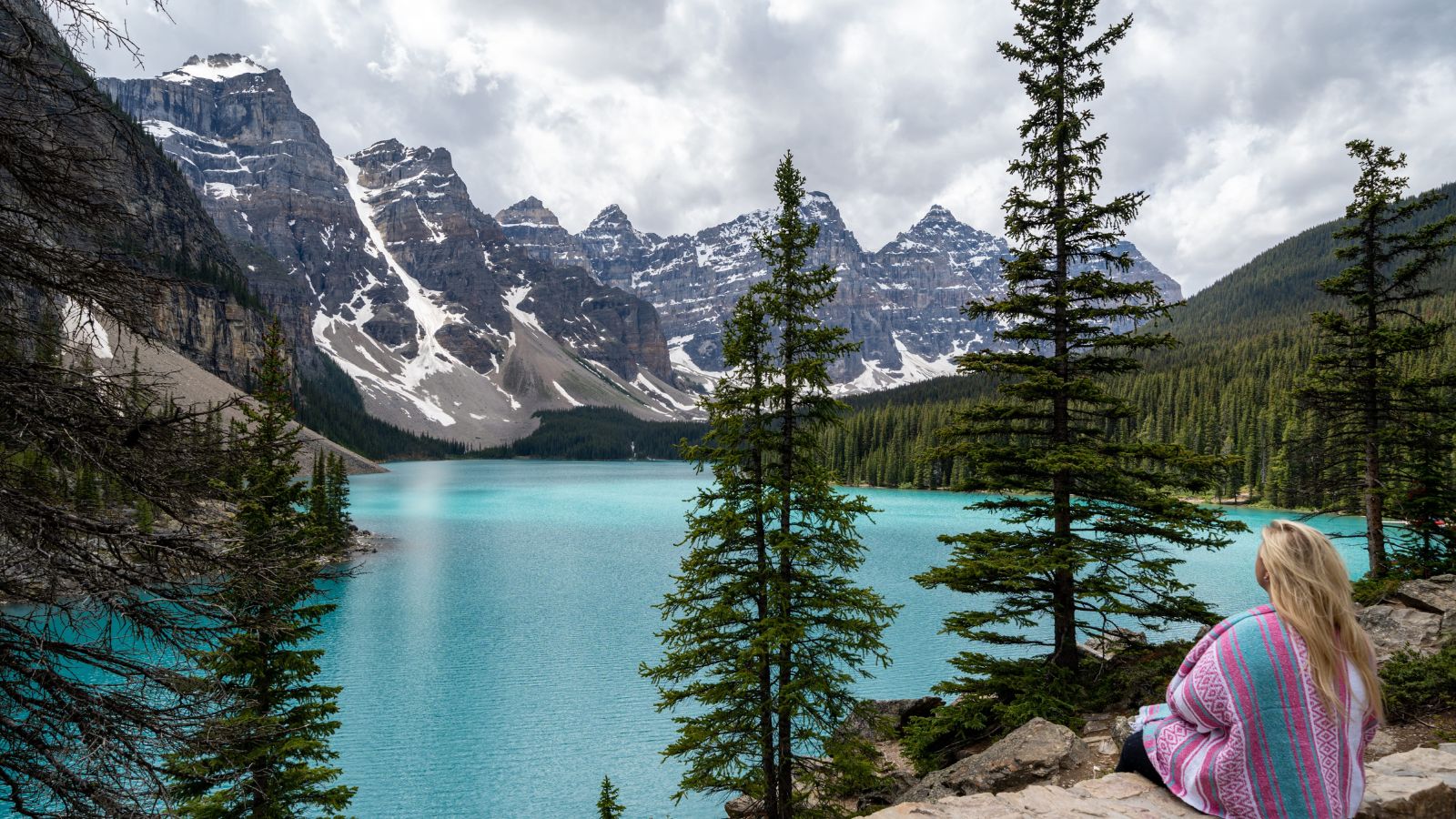 A photo that shows happy travelers enjoying the scenic mountain lake view in Banff National Park taking photos and relaxing.
