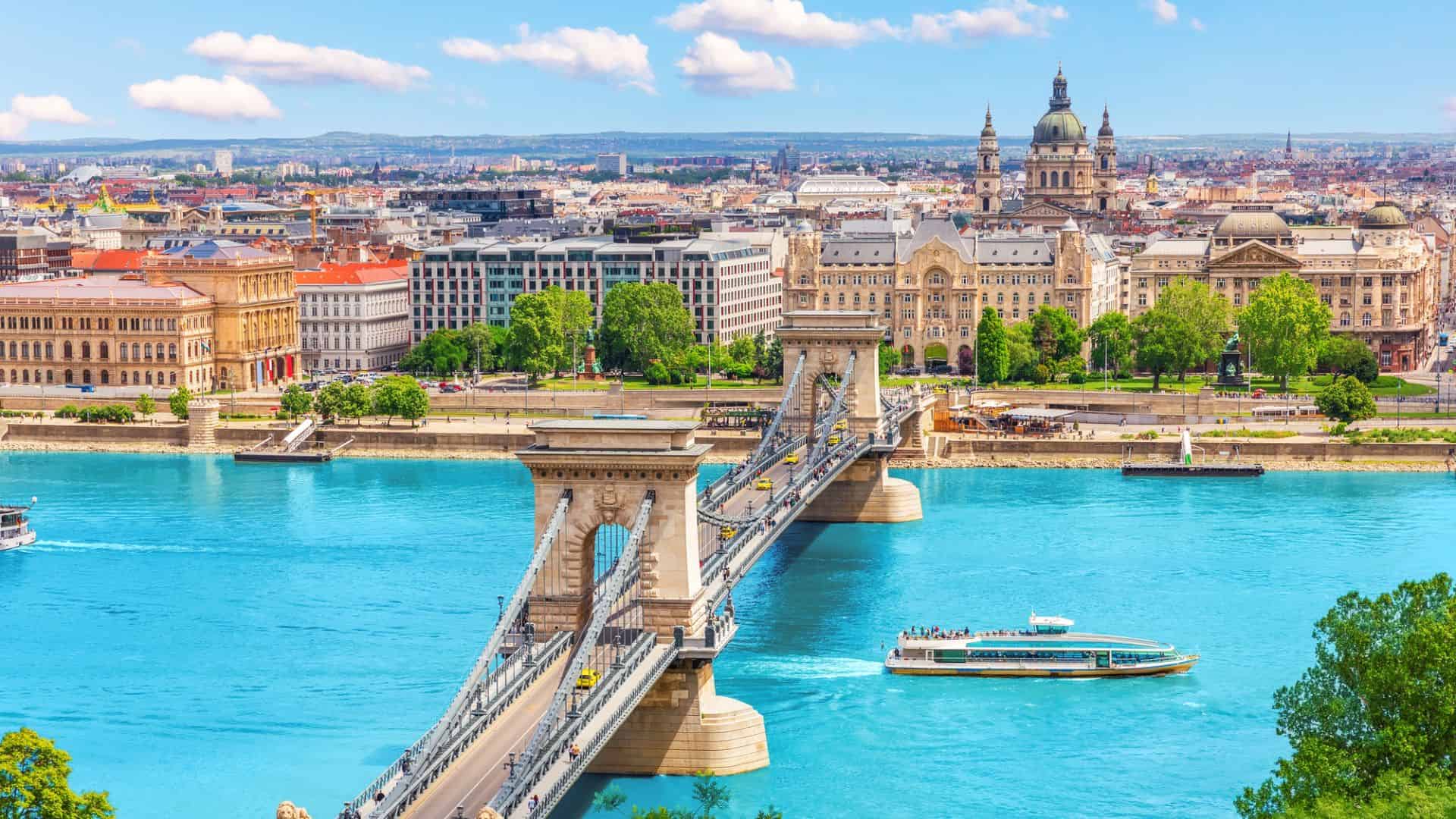 The Chain Bridge spans the Danube in Budapest, with historic buildings and St. Stephen’s Basilica visible in the background.