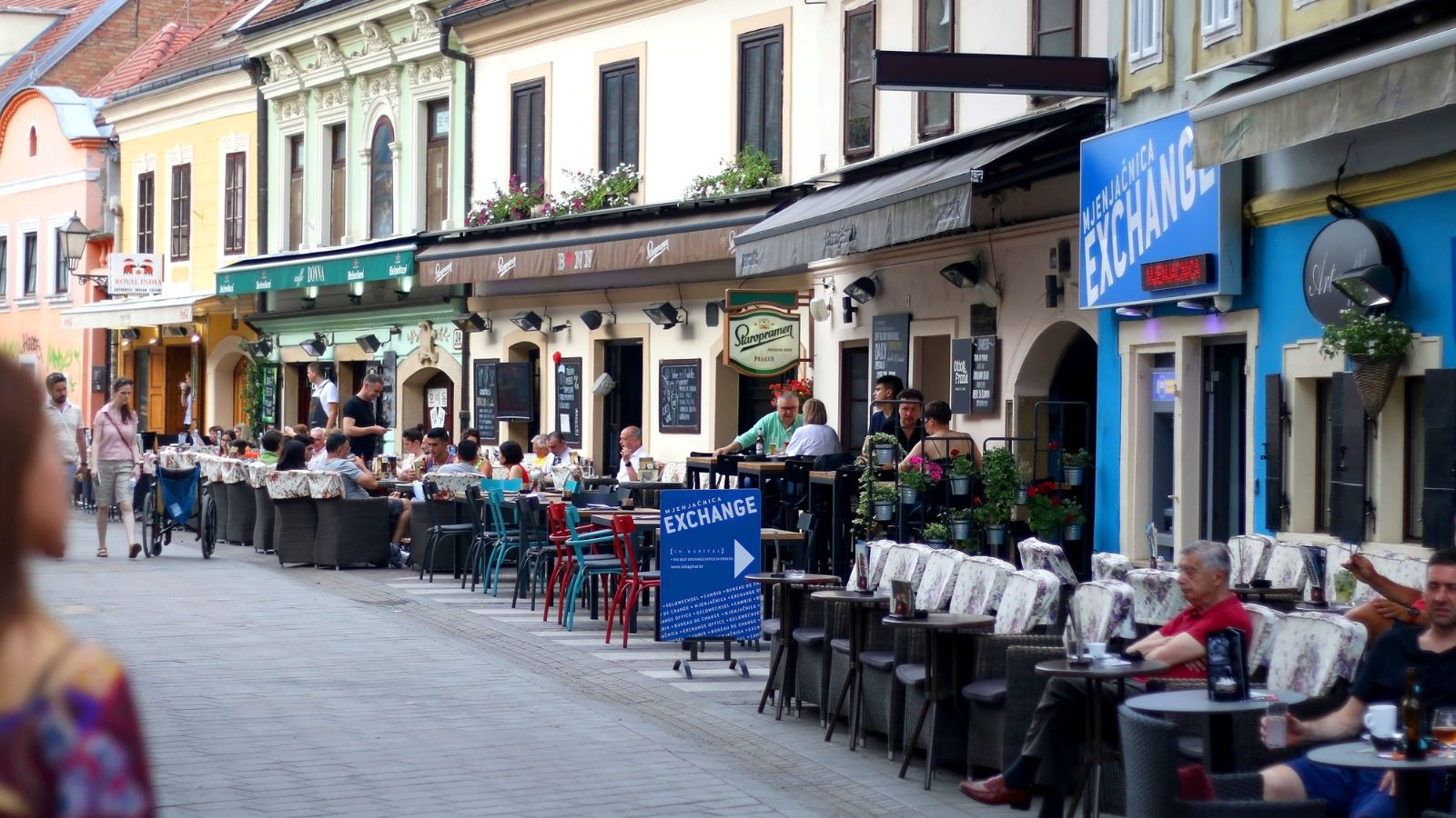 A photo of a travelers sitting at a cozy European restaurant with historic buildings and outdoor café tables.