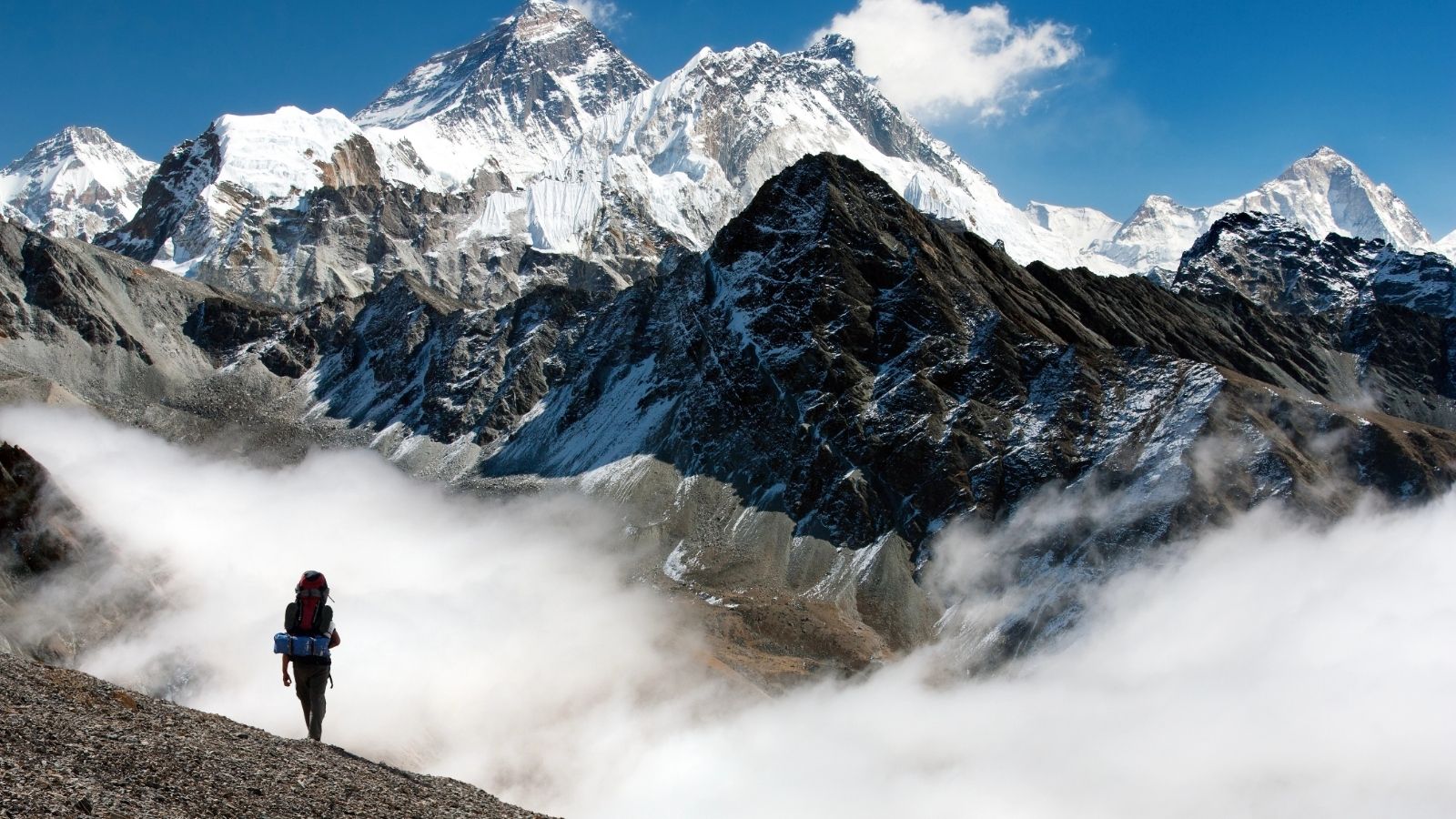 Hiker standing above clouds with dramatic Himalayan peaks on the Everest Base Camp trek.