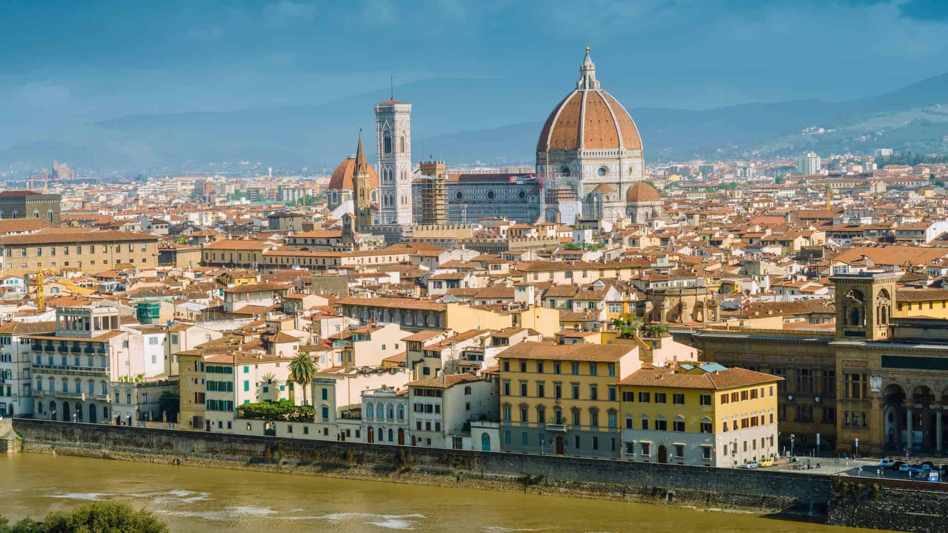 Florence, Italy with the red-domed Florence Cathedral, historic buildings, and the Arno River in the foreground.