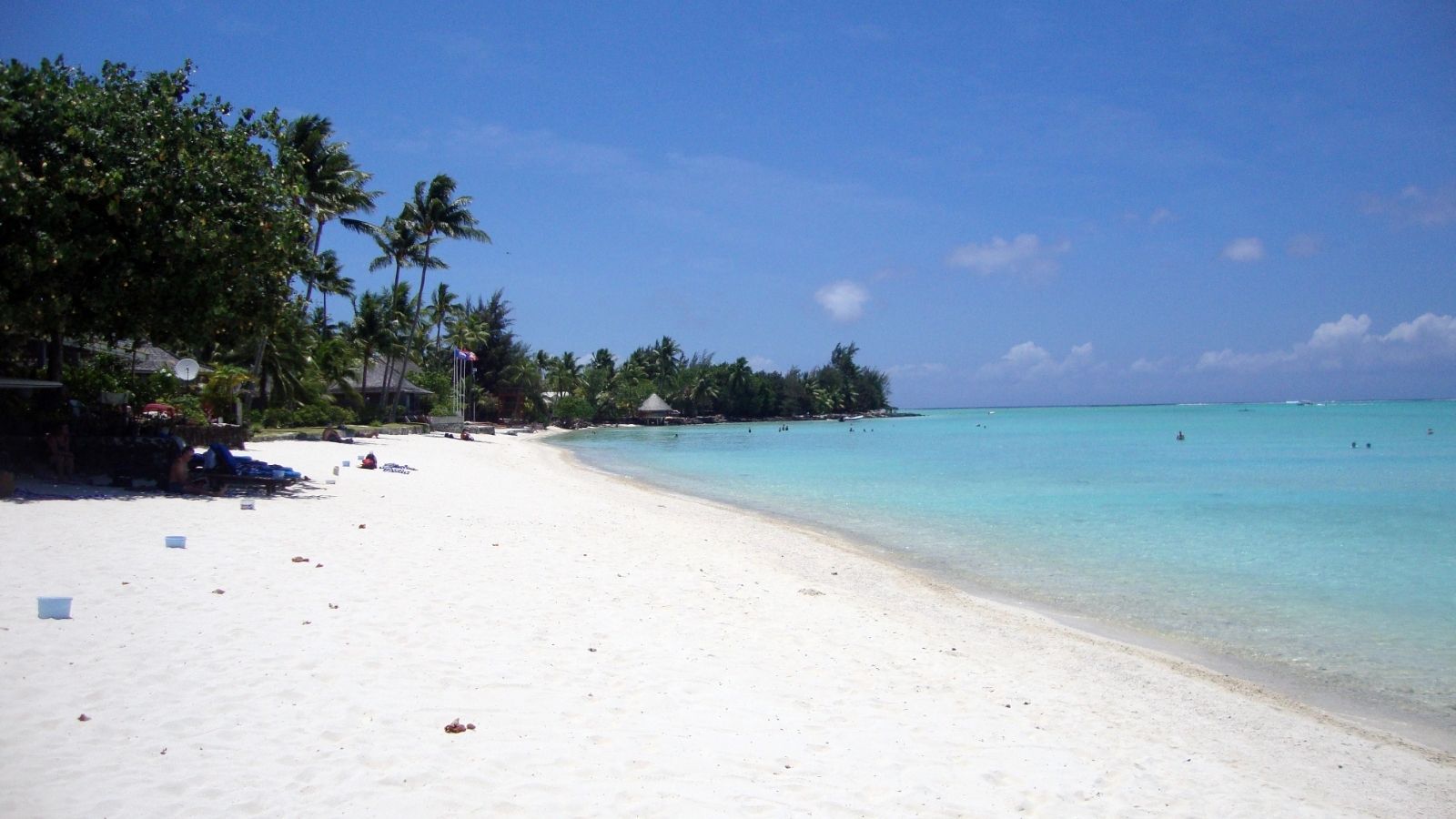 Palm-fringed white sand beach and calm turquoise lagoon at Matira Beach in Bora Bora.