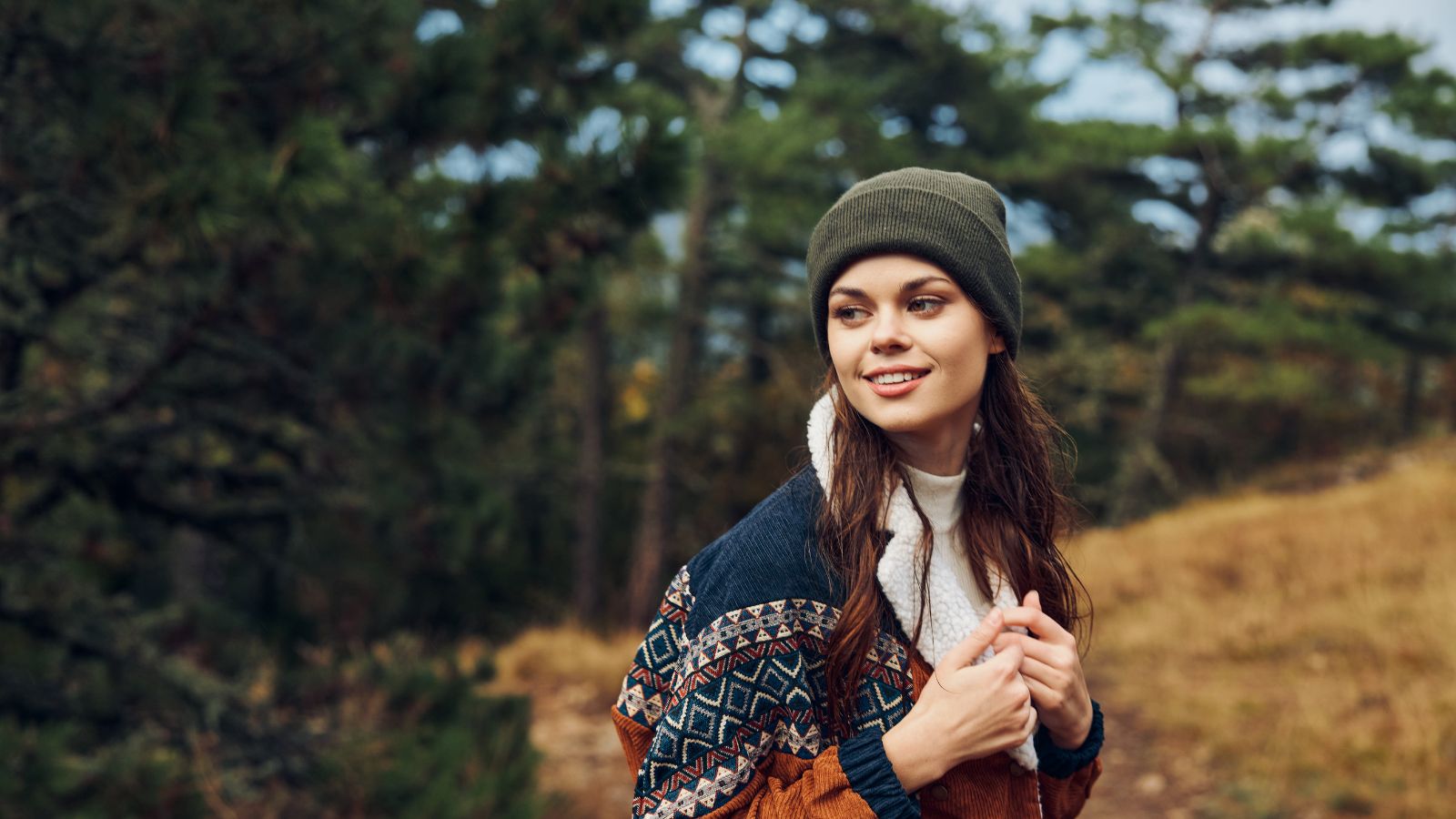 A photo of a happy traveler walking through a scenic Canadian park in layered clothing with light jacket.