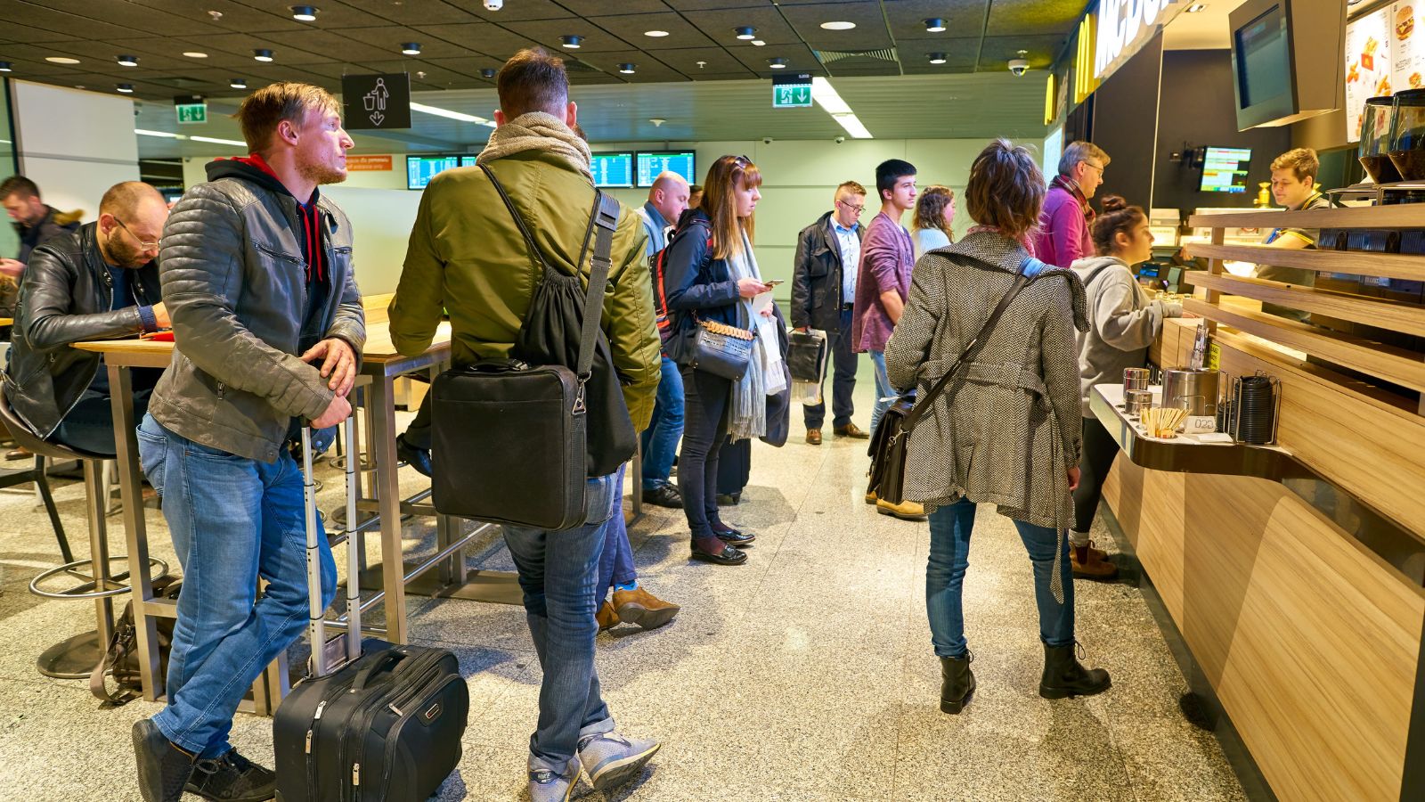 A photo of a crowded airport gate passengers lining up for boarding busy line overhead bins rush travel candid realistic.