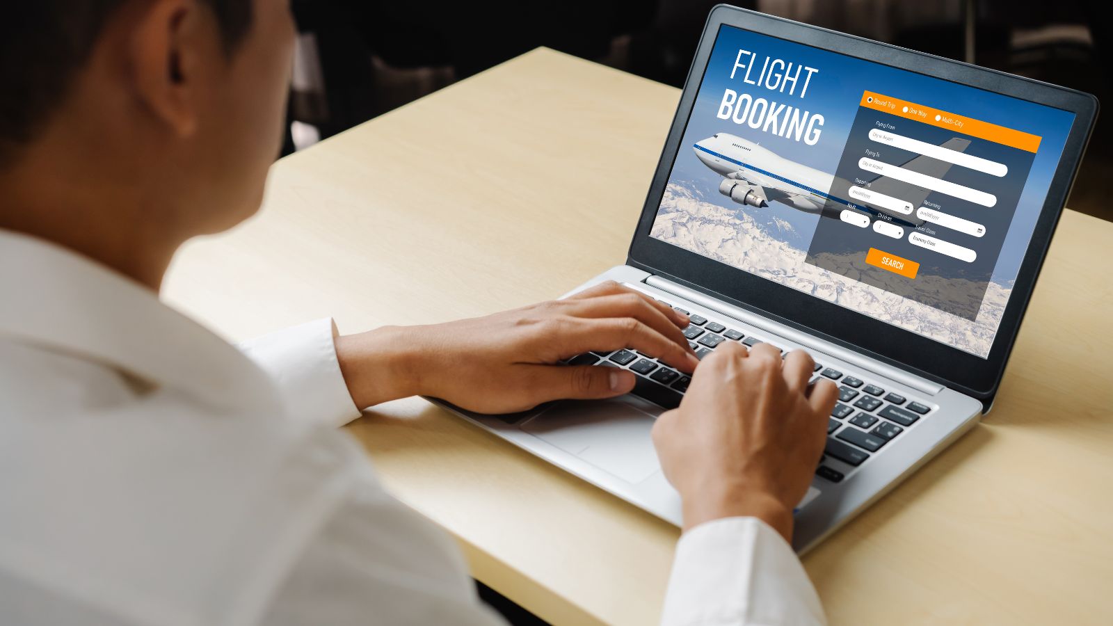A photo of a man facing laptop watching flight detail