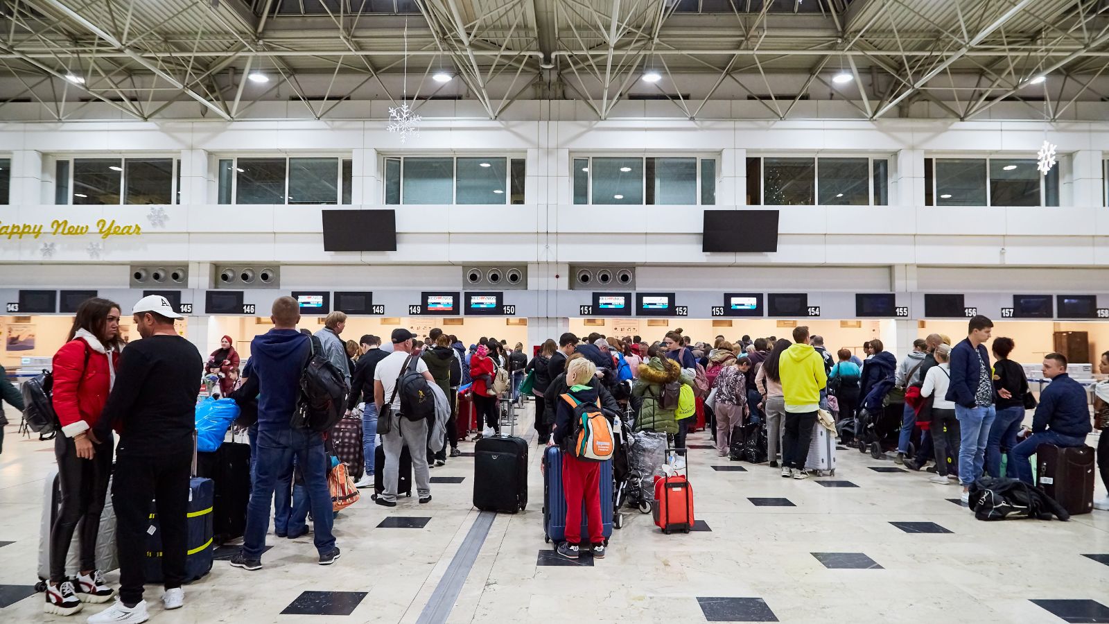 A photo of a busy airport terminal crowded travelers rushing with luggage long lines check in security stress travel candid realistic.