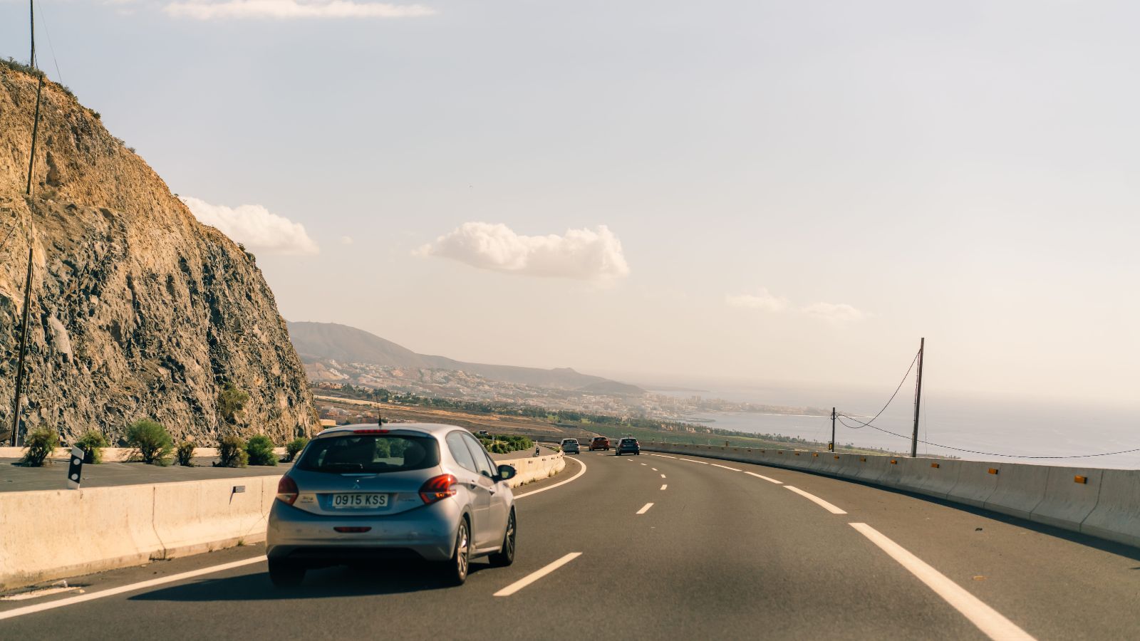 A photo of car driving along a beautiful coastal highway with ocean views and scenic landscape.