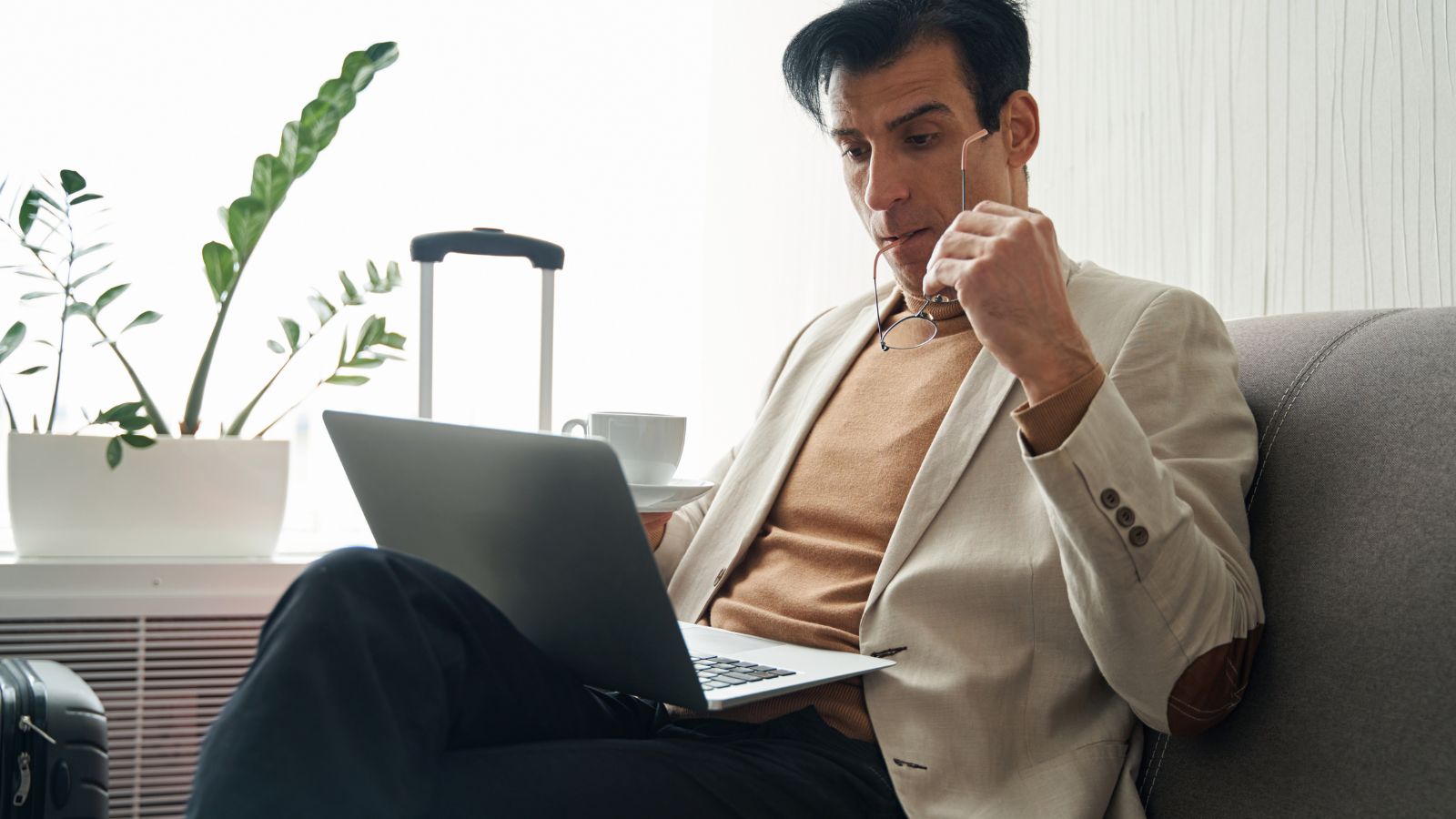 A photo of a traveler looking thoughtfully at different hotel prices and options on a laptop while planning a trip.