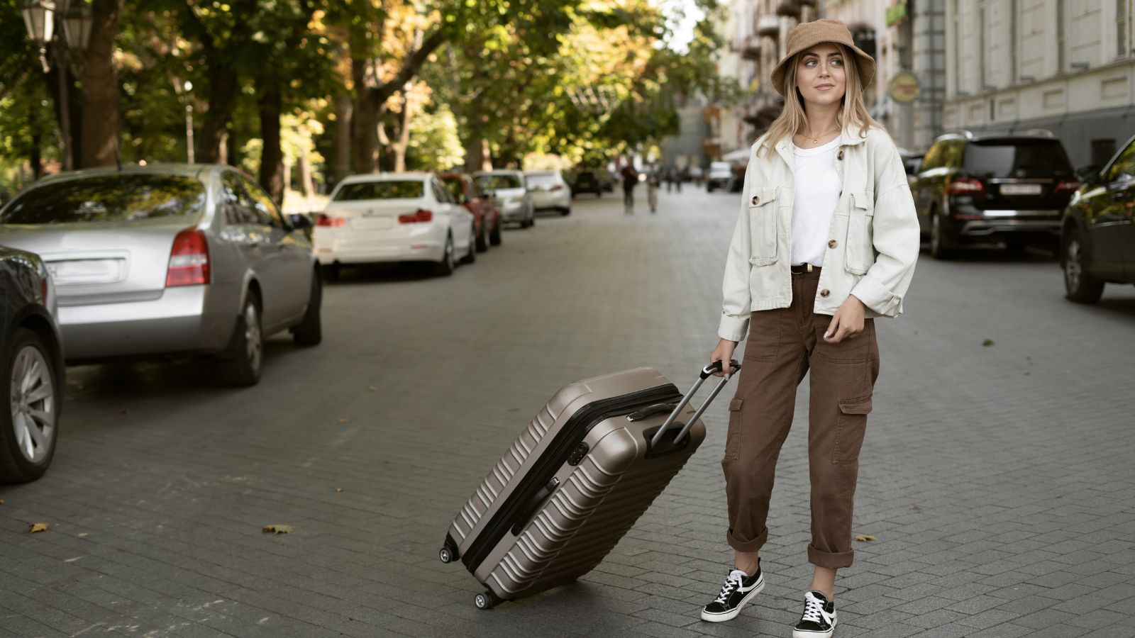 A photo of a traveler pulling a suitcase across a cobblestone street in a historic European city with narrow streets.
