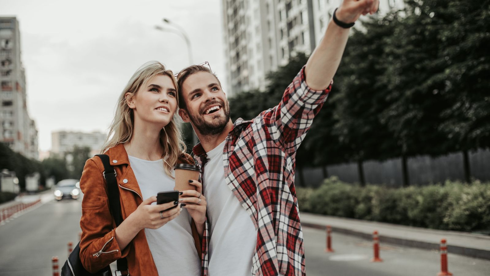 A photo of couple arriving in a new city with luggage, looking around with excitement and curiosity.