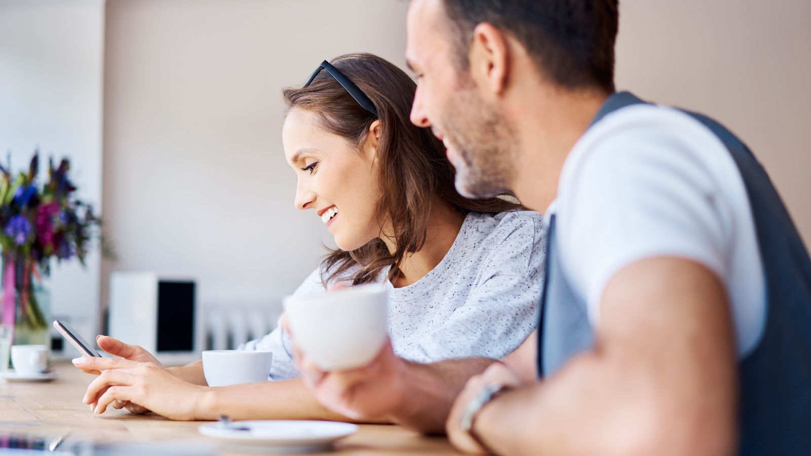 A photo of couple happily planning their trip together with a map and laptop at a café table.