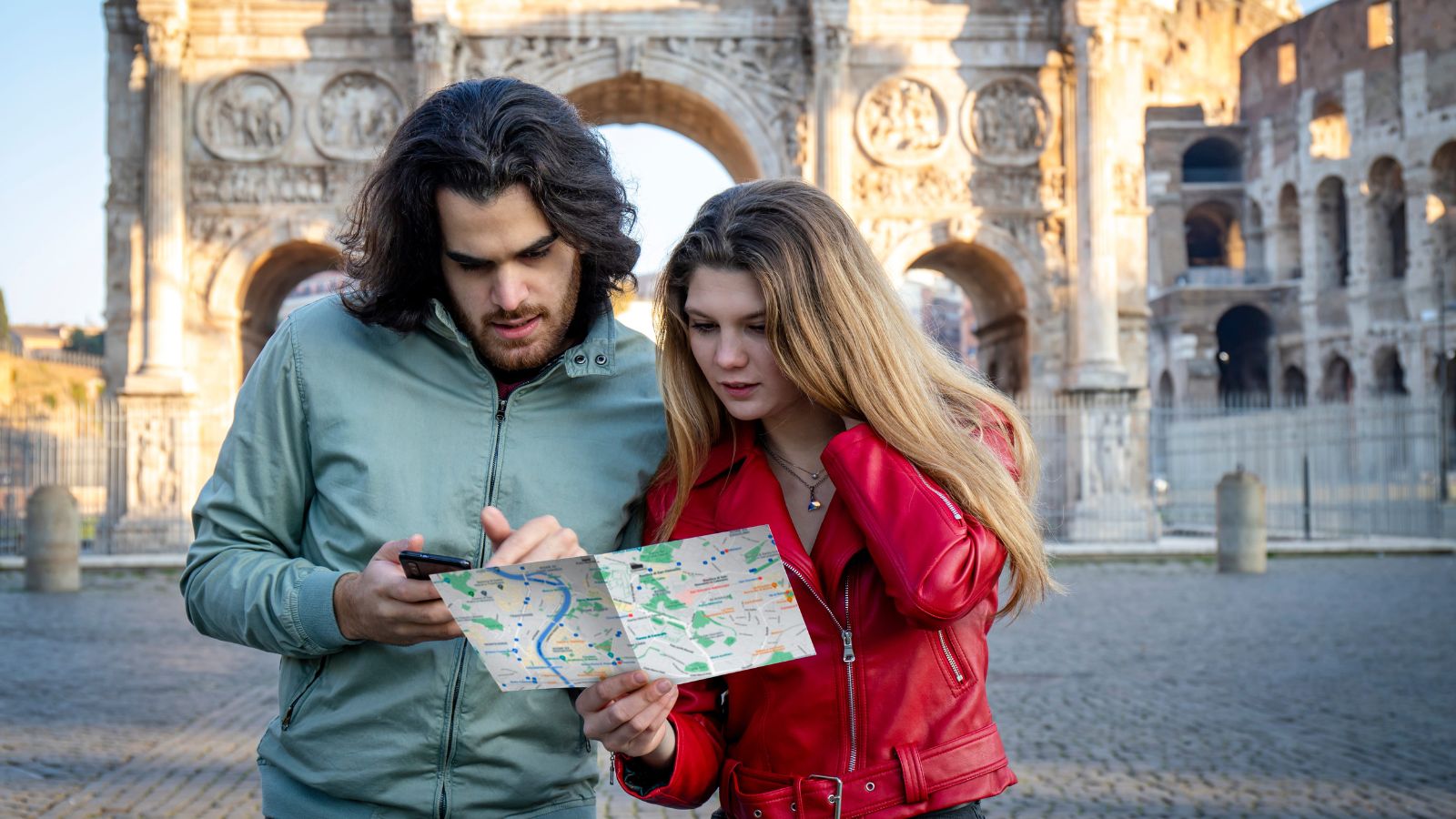 A photo of a couple planning trip with busy itinerary notebook phone maps looking slightly overwhelmed tight schedule travel planning candid natural light.