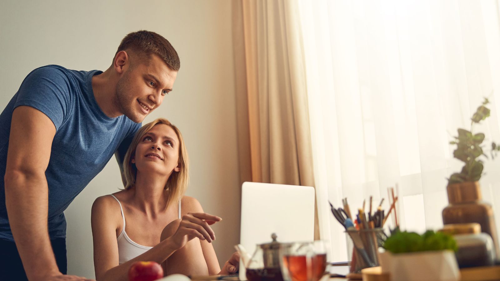 A photo of couple, facing laptop, lively talking about something.