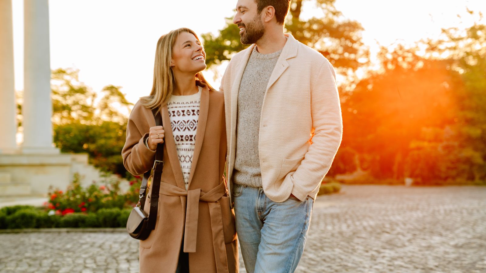 A photo of romantic couple walking in scenic quiet city or park, calm surroundings, enjoying view, relaxed travel, holding hands, natural light, candid travel photography.