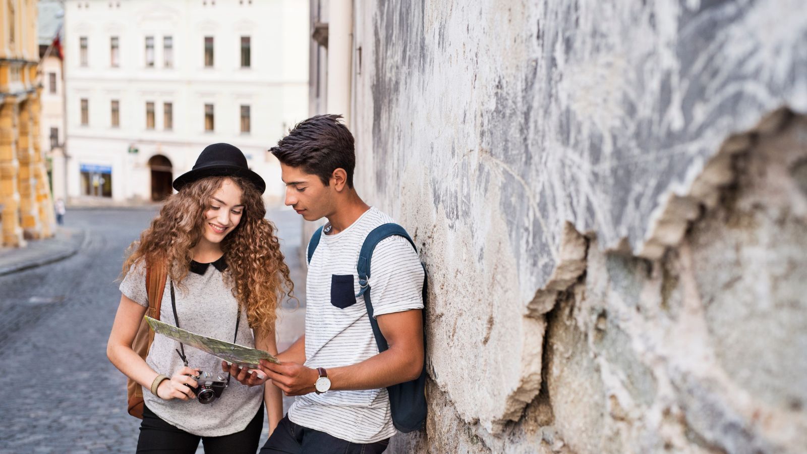 A photo of couple looking at a map in a historic city street, discussing directions and making decisions together