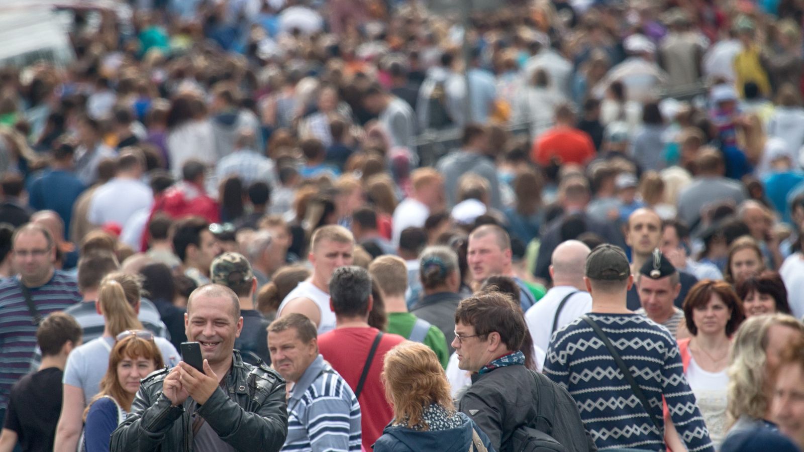 A photo of traveler walking through crowded tourist area during peak time looking slightly overwhelmed.