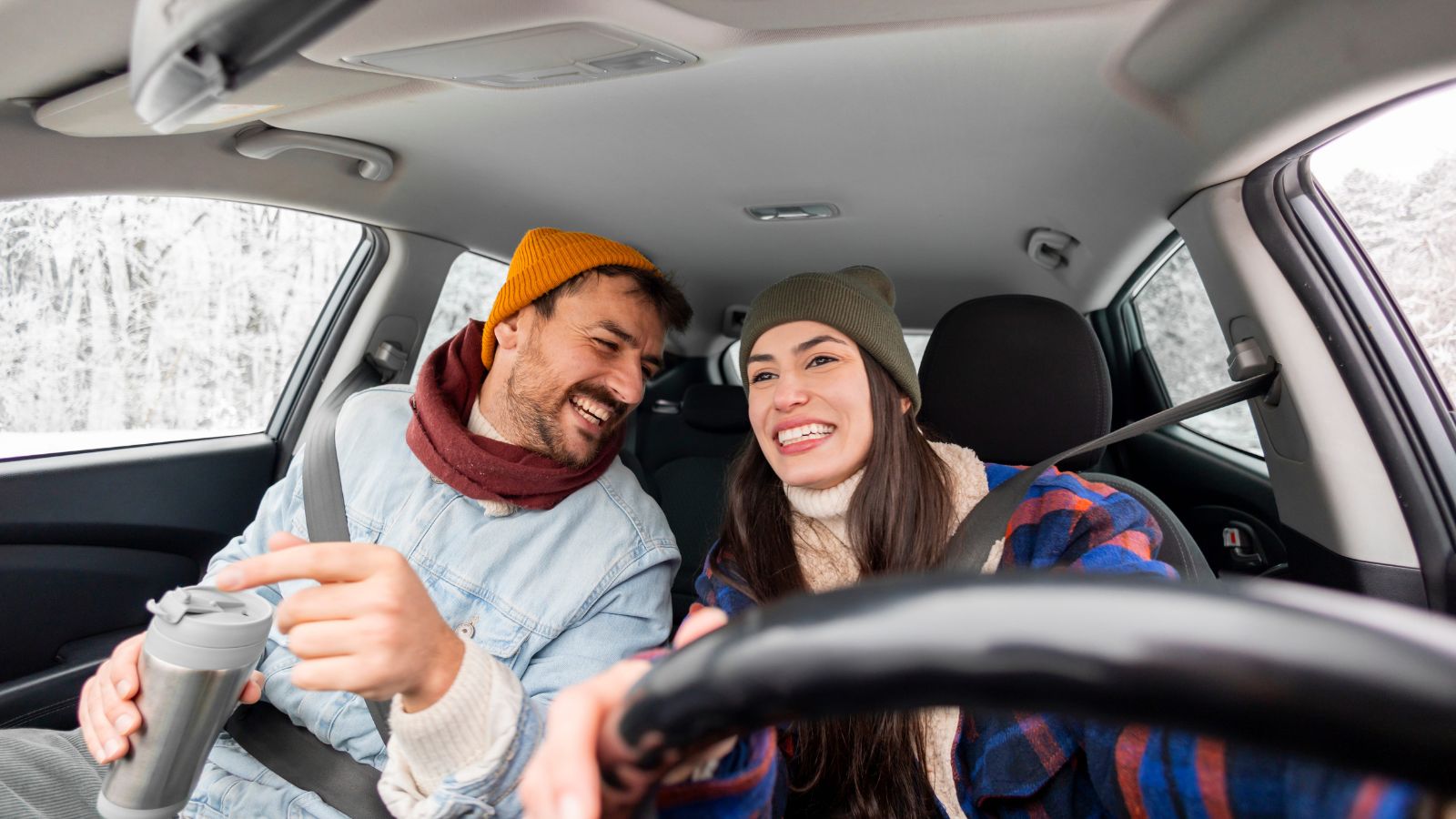 A photo of happy travelers back in the car, smiling and relaxed, driving through a scenic landscape after a short break.