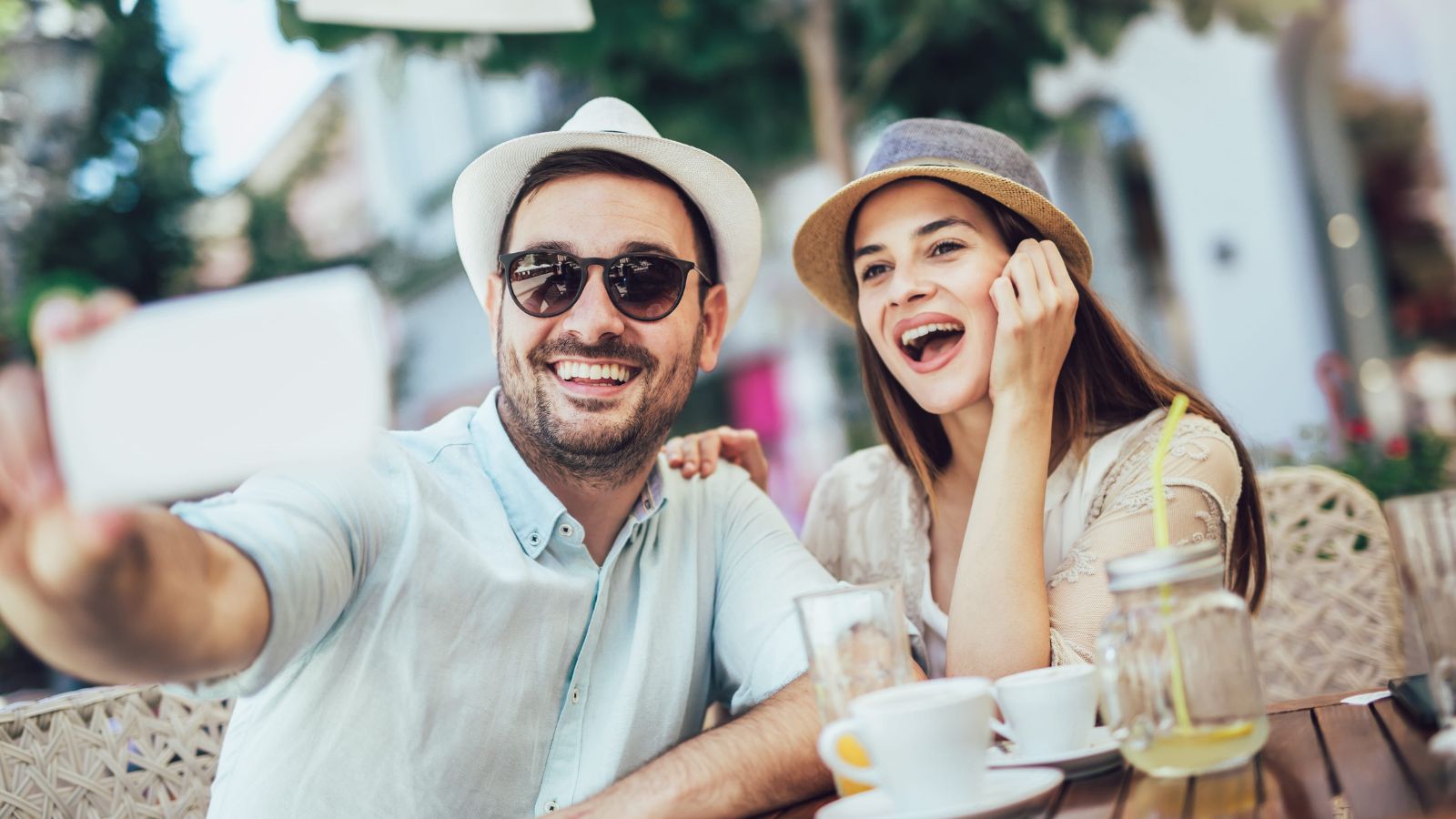 A photo of couple enjoying a relaxed travel moment together at an outdoor café, smiling and comfortable.