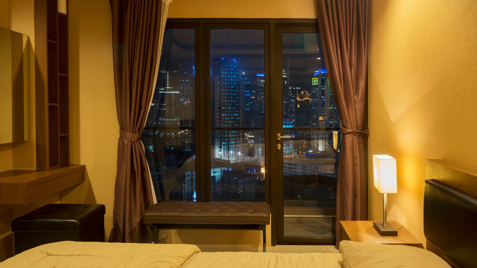 A photo of peaceful hotel room at night on a high floor with soft lighting and city view