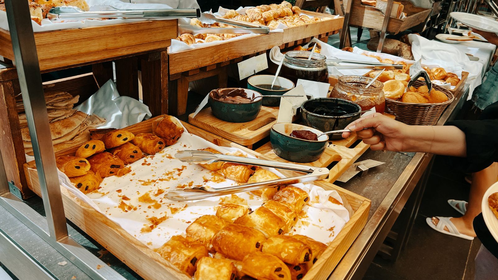 A photo of a hotel breakfast buffet with fresh fruit, pastries, coffee and juice in a bright modern dining area.