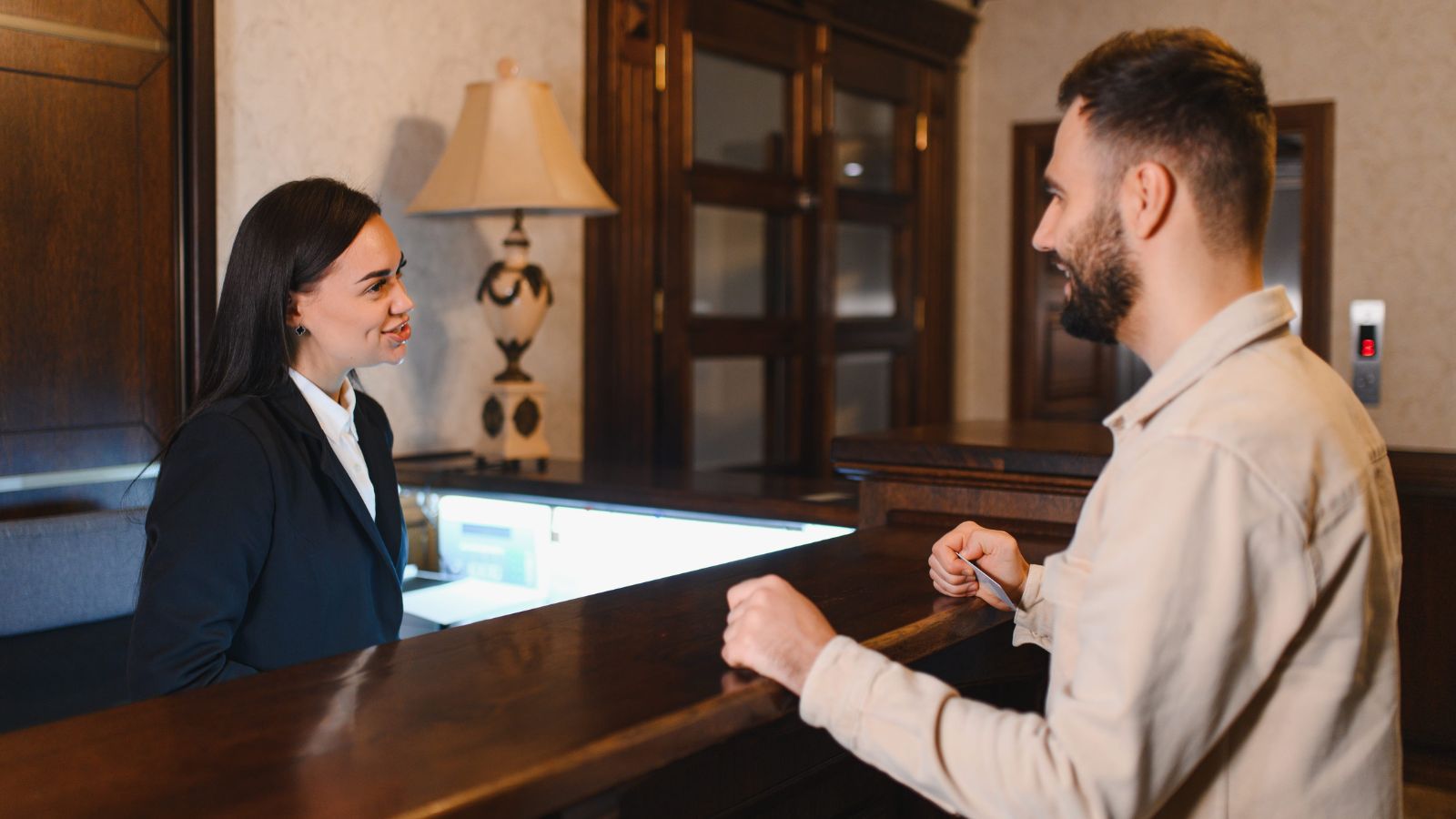 A photo of a man inquiring something at a woman in the front desk.