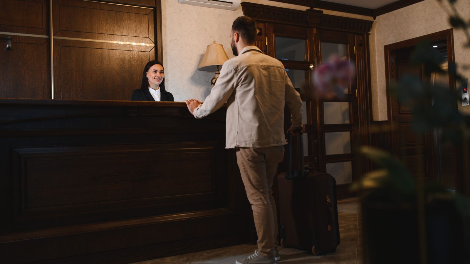 A photo of a hotel guest checking in at front desk receiving key card neutral interaction modern hotel lobby candid realistic.