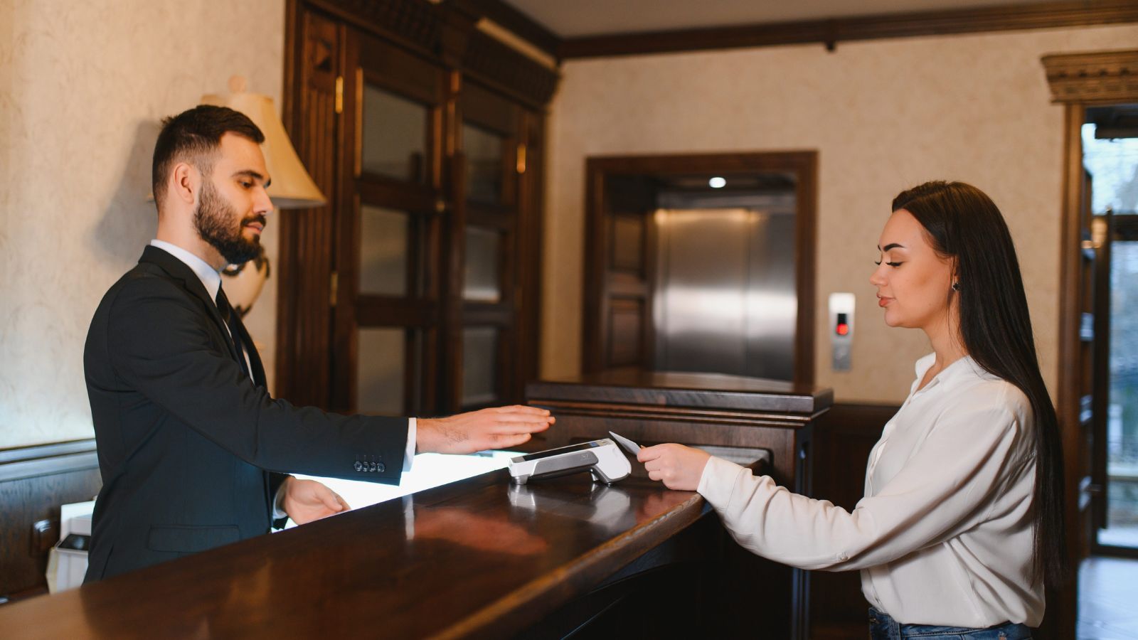 A photo of a hotel reception check in traveler receiving key card front desk modern hotel lobby natural candid.