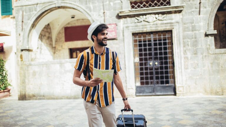 A photo of a smiling man, carrying a luggage