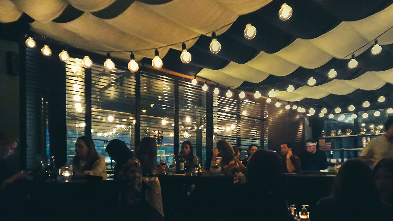 A photo of a lively European restaurant at night with people dining around 9 pm under warm lights.
