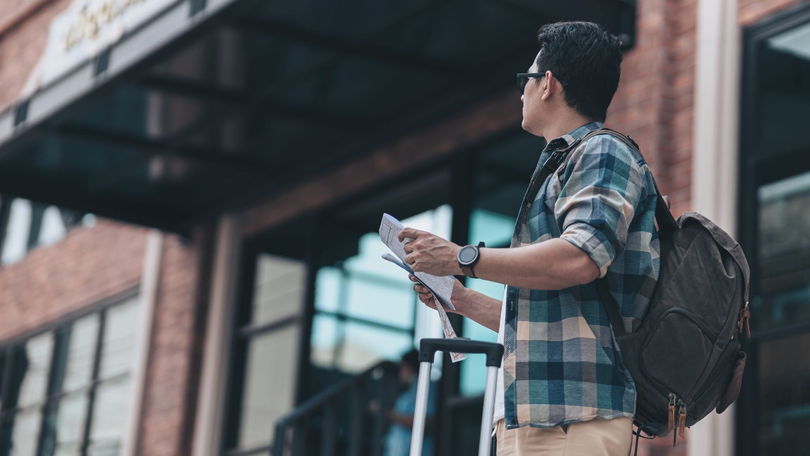 A photo of a raveler standing outside hotel looking frustrated or confused assessing surroundings urban street city background realistic travel moment natural light candid.