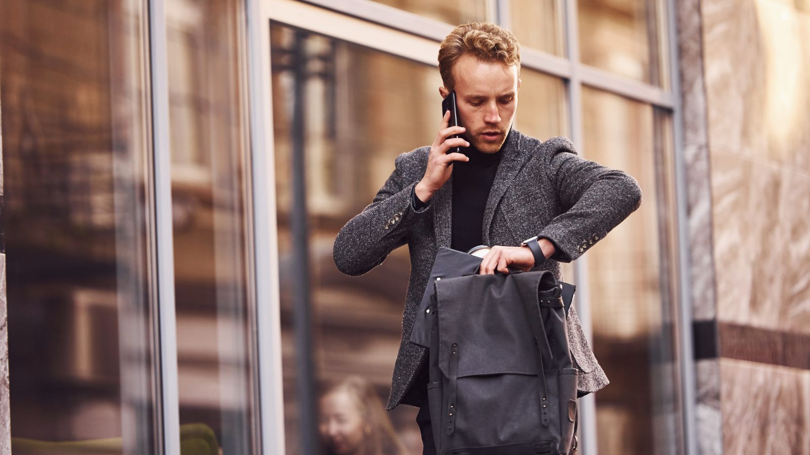 A photo of a tourist walking fast in city checking watch or phone feeling rushed crowded travel schedule stress candid.