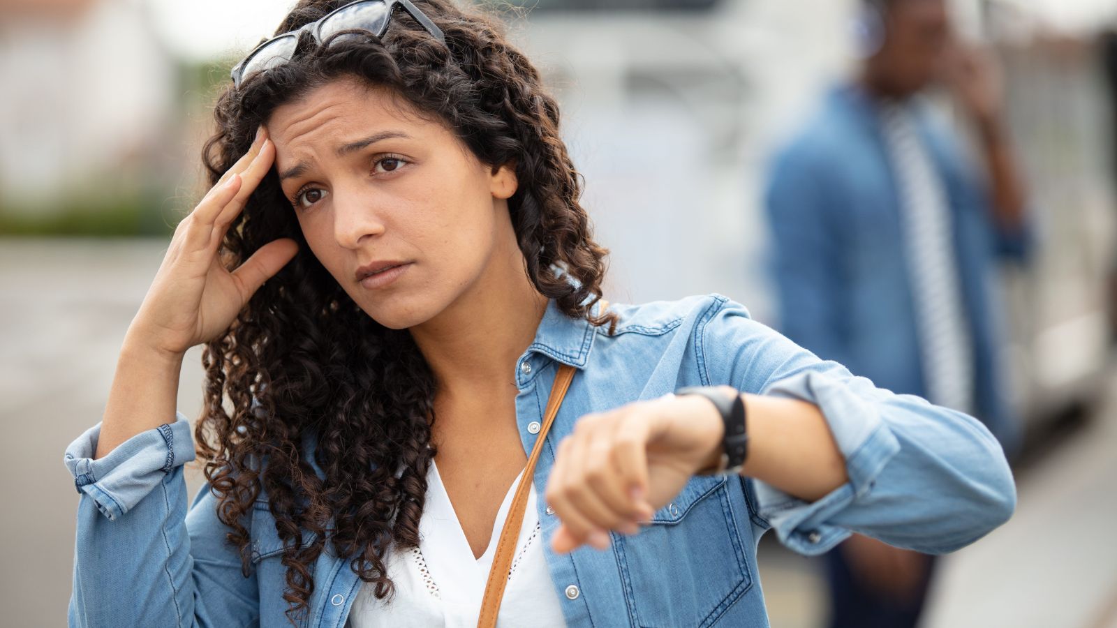A photo of a tourist walking fast in city looking tired checking watch or phone travel fatigue stress candid.