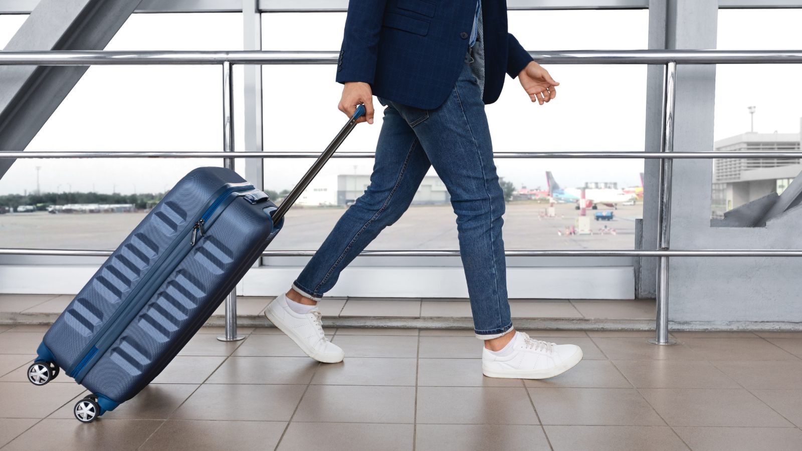 A photo of a traveler walking through airport with small carry on luggage minimal travel lifestyle natural candid shot.