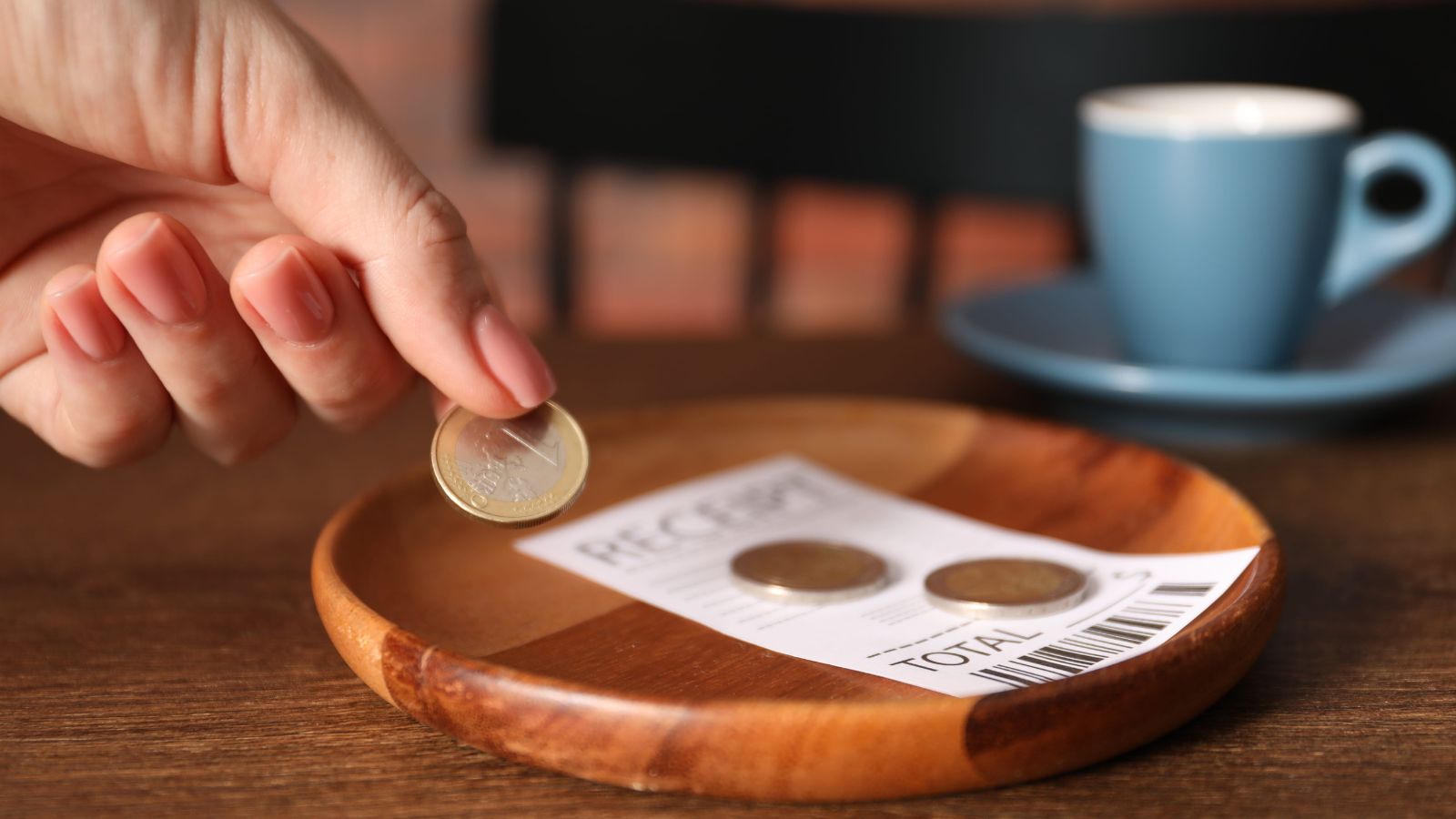 A picture that describes a traveler leaving small coins or rounding up the bill on a restaurant table in Europe.