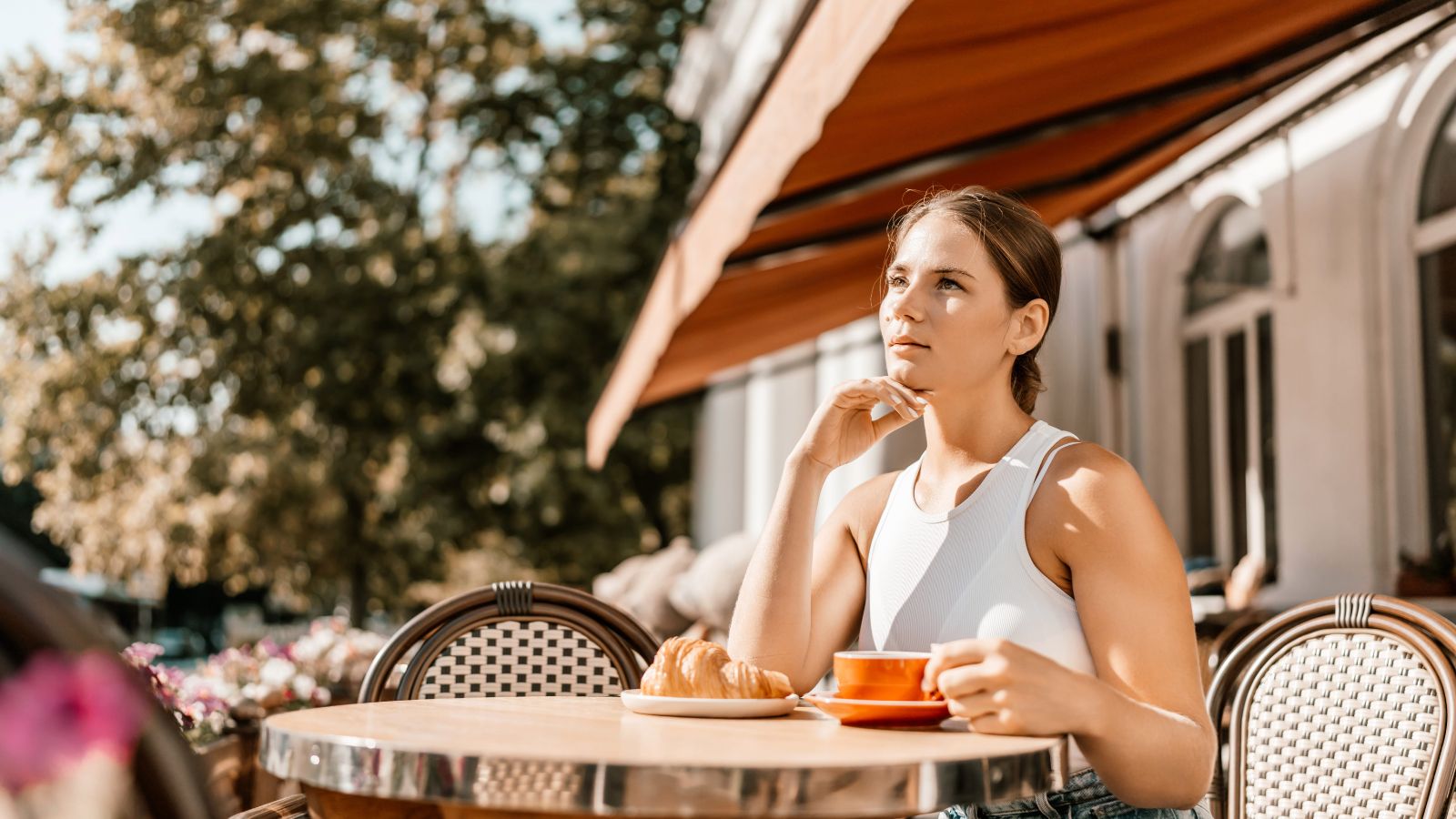 A photo of a traveler sitting at quiet café enjoying breakfast relaxed thoughtful peaceful atmosphere slow travel natural light calm morning travel experience candid.