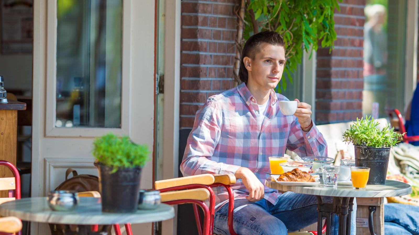 A photo of a traveler relaxing at an outdoor café in a charming European street, observing daily life around them.