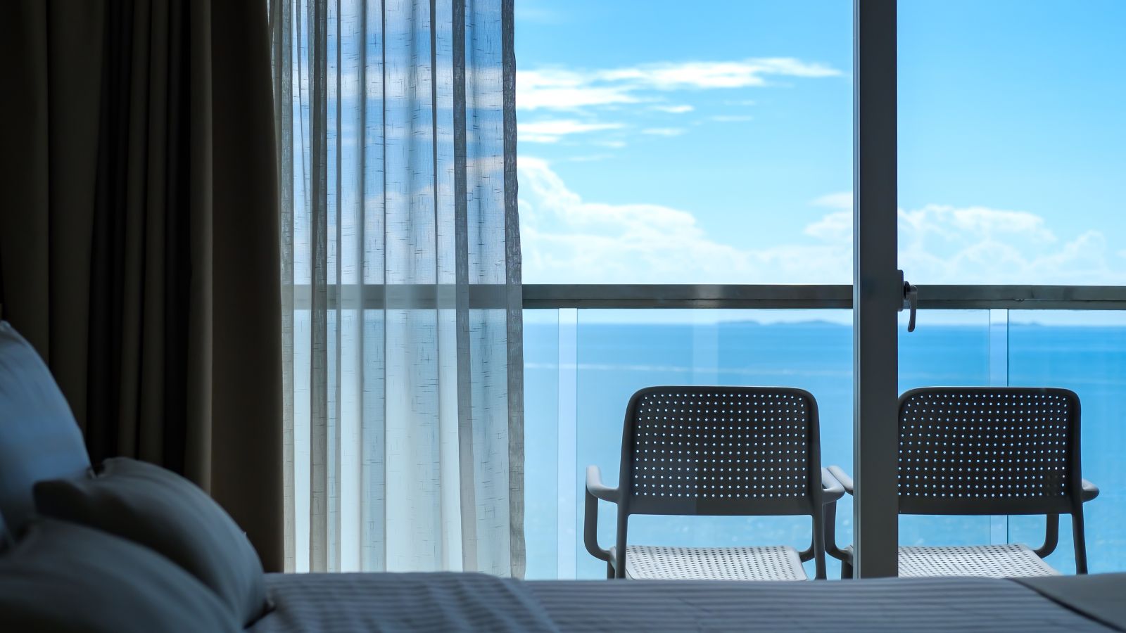 A photo of romantic hotel suite with balcony ocean view soft morning light.