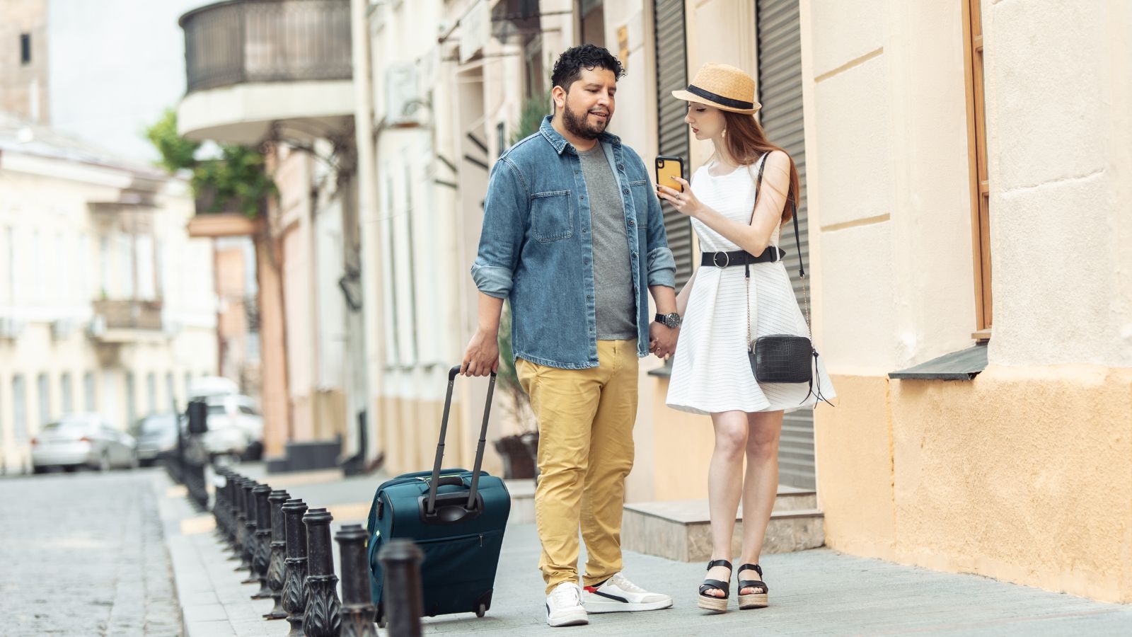 A photo of a happy couple arriving in a beautiful European city with luggage, excited to start their vacation.