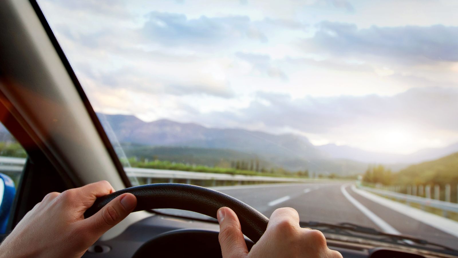 A picture that shows a travelers driving on an open scenic highway during a road trip, bright sky and sense of adventure.