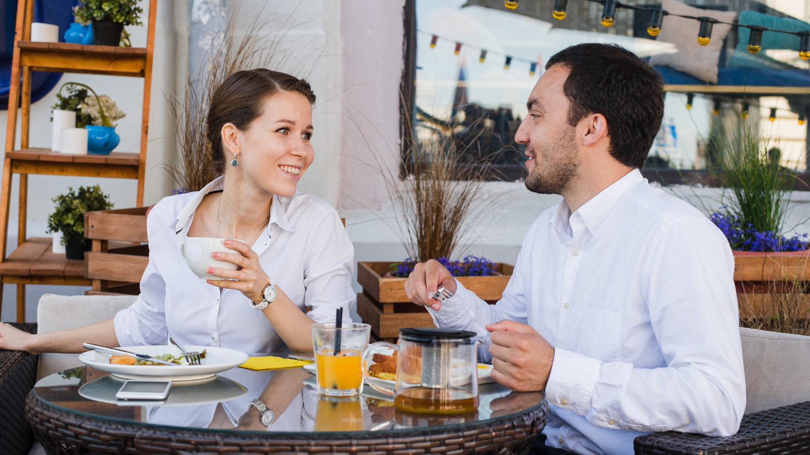 A photo of happy travelers enjoying food and conversation at a charming outdoor European restaurant.